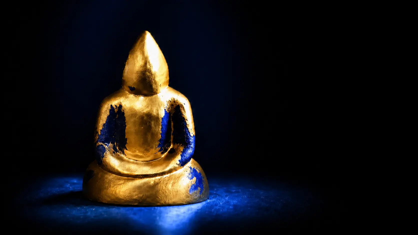 Statue dorée avec reflets bleus, symbole de présence silencieuse et d’exploration intérieure